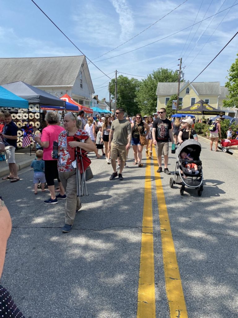A street full of vendors and fairgoers.